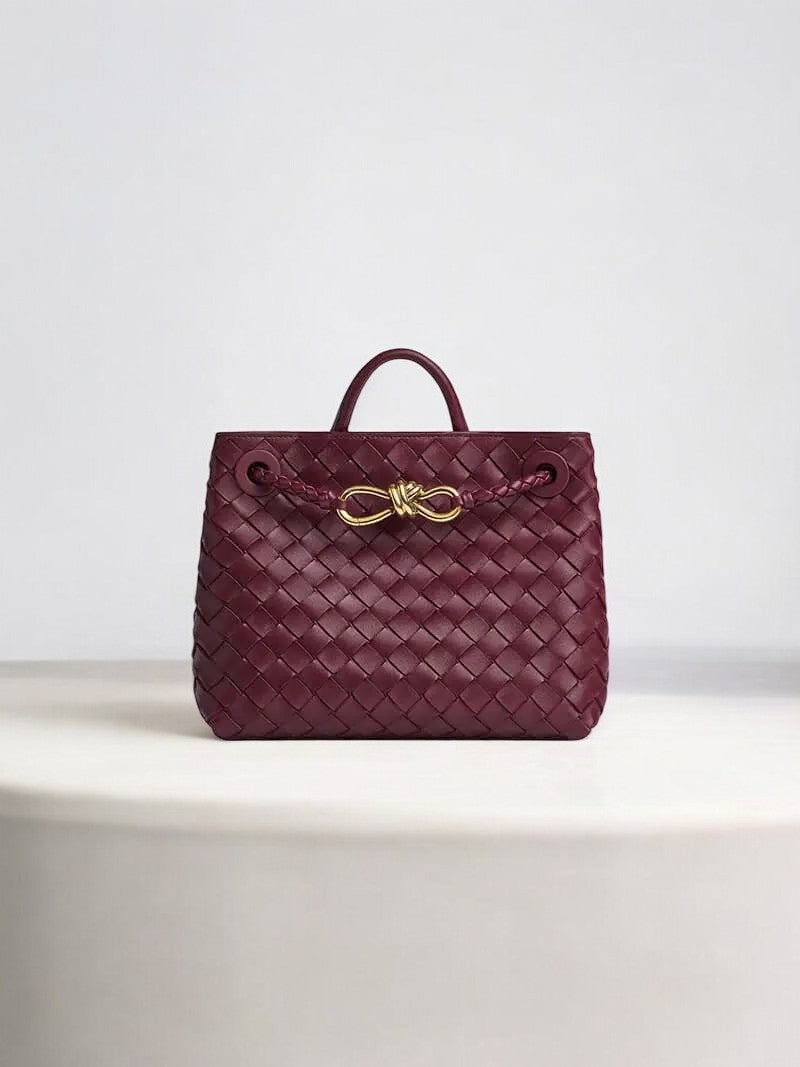 Burgundy woven leather handbag with gold knot clasp and top handle
