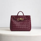 Burgundy woven leather handbag with gold knot clasp and top handle