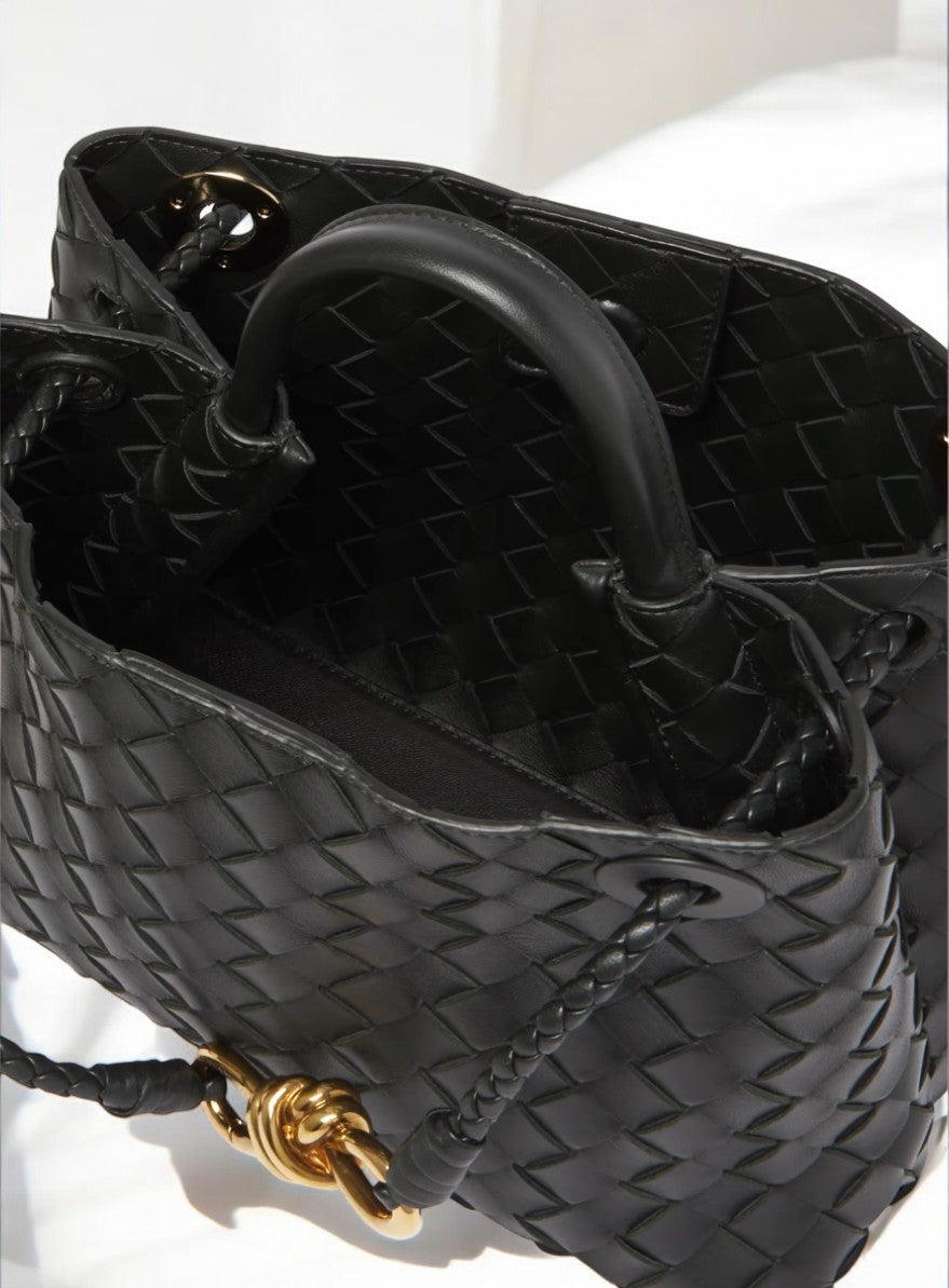 Interior detail of black woven leather handbag with gold rope clasp and braided handles
