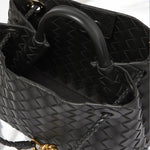 Interior detail of black woven leather handbag with gold rope clasp and braided handles