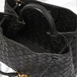 Interior detail of black woven leather handbag with gold rope clasp and braided handles